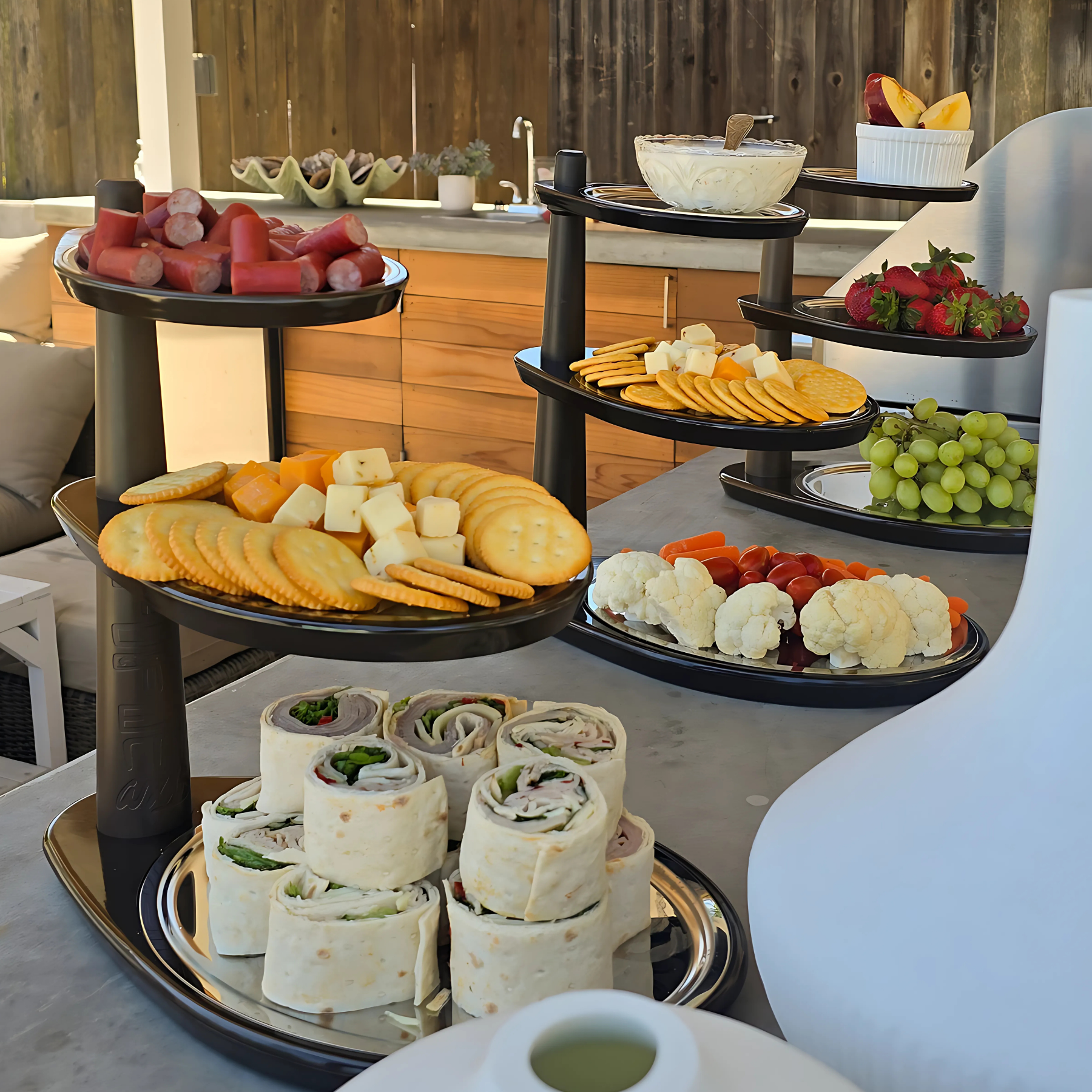 Assorted food items on tiered trays on a table outdoors.