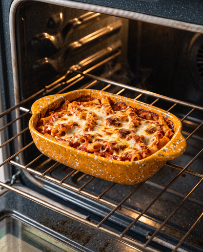 Pumpkin splatterware baking dish of baked ziti on an oven rack