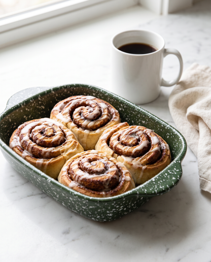 Forest Green splatterware baking dish of cinnamon rolls on a white marble countertop